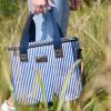 Model holding blue striped picnic bag in grassy outdoor setting