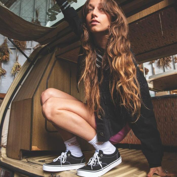 Model with long hair crouching wearing vans shoes, sock and a big black jumper